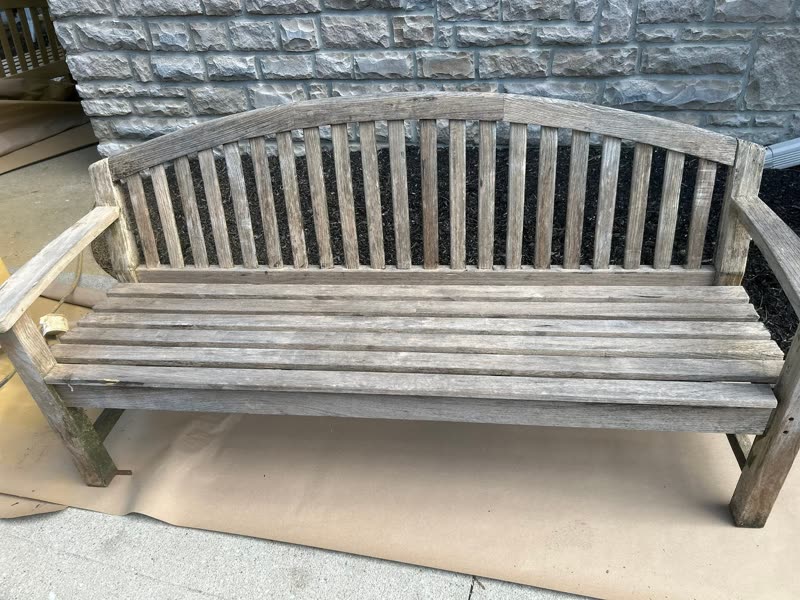 Garden bench before — sun-worn, weathered grey wood